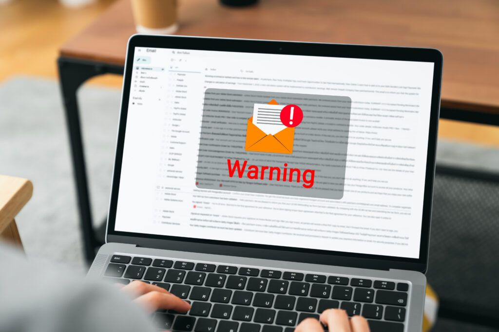 Hand using laptop with shows a warning screen of new email notifications hack password and personal data Concept of cyber crime